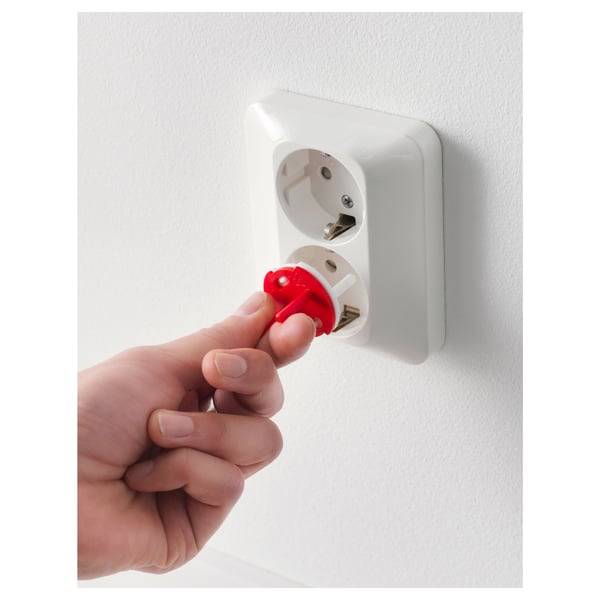 Hand inserts red key into white socket plug, securing childproof safety cover.