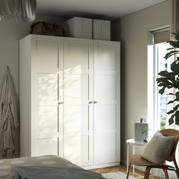 Modern bedroom with PAX wardrobe, accessories, wooden chair, plant, and lamp.