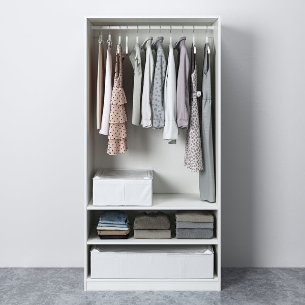 A white PAX wardrobe organises clothes. It has hanging garments, folded clothes, and storage boxes.