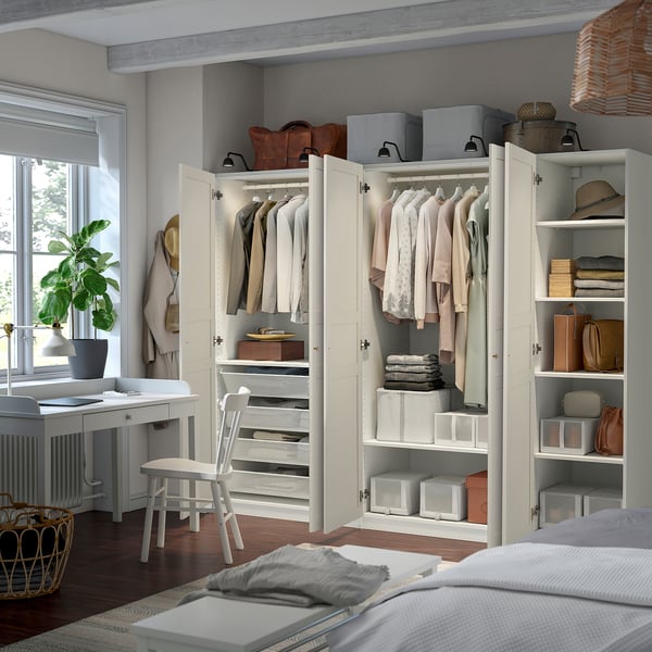 Organised bedroom closet with PAX wardrobe, shelves, and drawers for clothes and accessories. Integrated lighting highlights items.