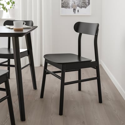 Black RÖNNINGE chair on light floors, next to small table with mug and coaster.