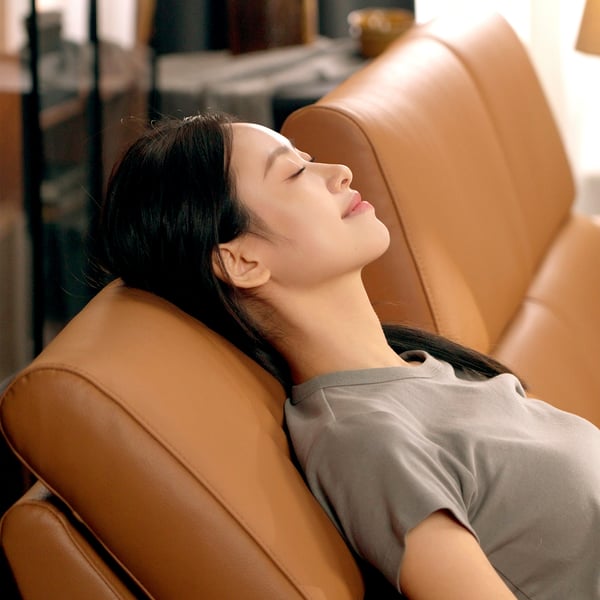 A person reclines comfortably on a RULLERUM sofa with built-in lumbar support and adjustable backrest.