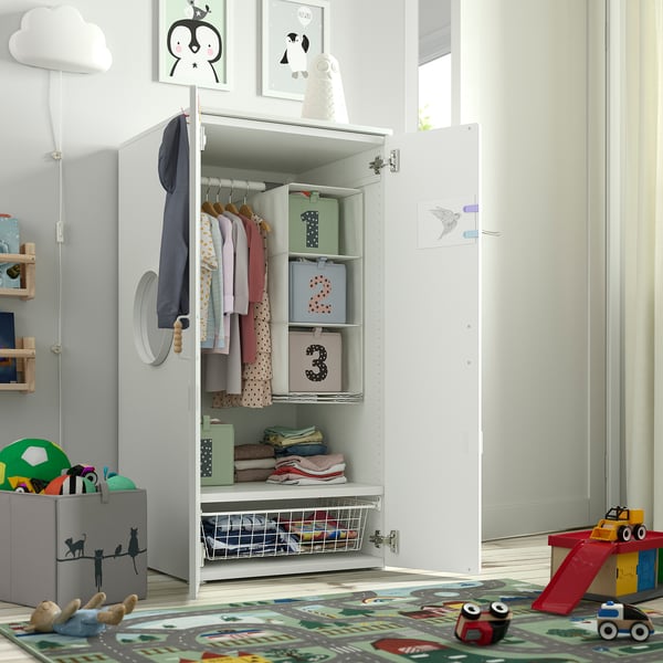 Kids wardrobe with open door, clothes hangers, boxes, and toys on colourful rug.