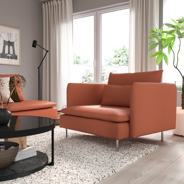 Modern living room with large orange SÖDERHAMN armchair, white curtains, and round coffee table by window.