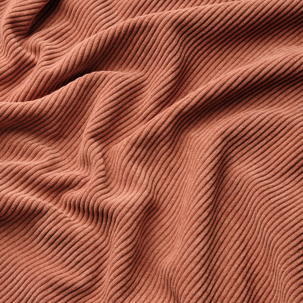 Soft, textured fabric in warm reddish-orange hue, likely part of a cosy sofa cover.