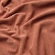 Soft, textured fabric in warm reddish-orange hue, likely part of a cosy sofa cover.