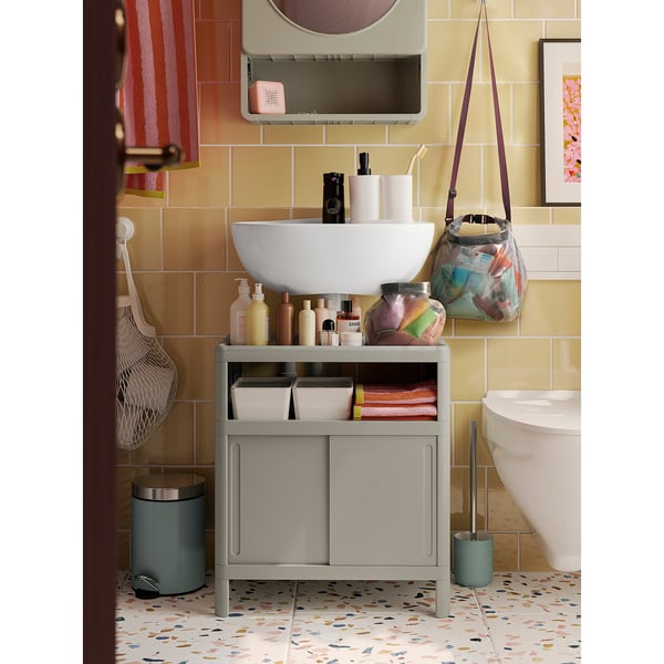 Colourful bathroom storage bag hangs near sink, larger than toilet brush, smaller than mirror.