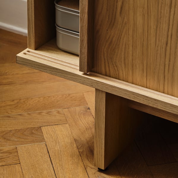 Wooden tv stand detail; adjustable feet, sliding doors, quality craftsmanship.