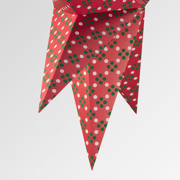 Bright red paper star with green and white dots, folded into intricate 3d shape.