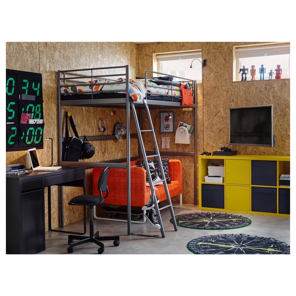 Modern bedroom with black SVÄRTA loft bed, ladder on right, desk, orange chair, flat screen tv, colourful rugs.
