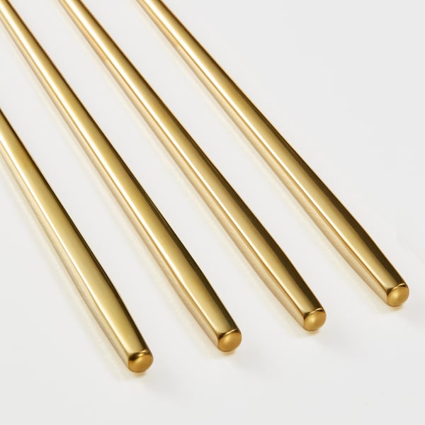 Six sleek, gold-colored chopsticks arranged neatly on a white surface, showcasing their smooth, polished finish and square tips.