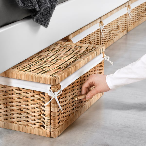 Hand opening woven storage basket under bed, showing easy access and handle detail.