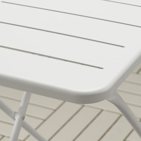 Close-up of folded white TORPARÖ table, showcasing durable, powder-coated steel surface with drainage slits.