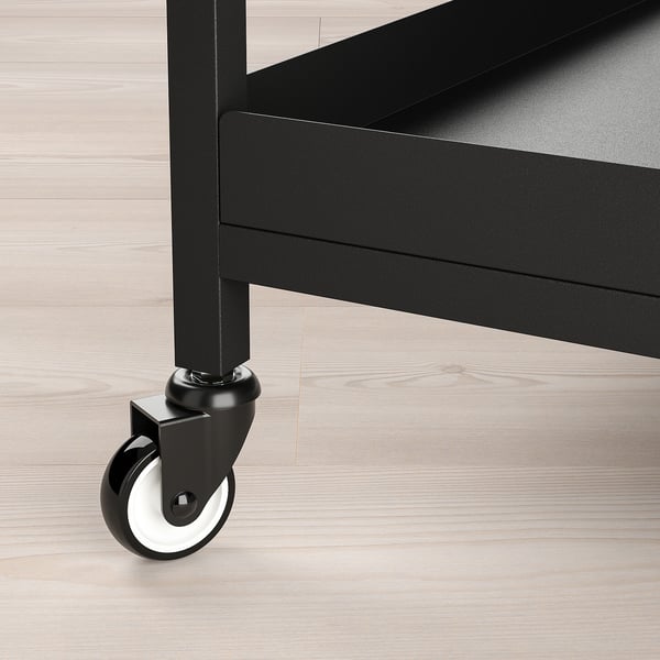 Black metal trolley with smooth-rolling casters on wooden floor, showcasing sturdy construction and sleek design.