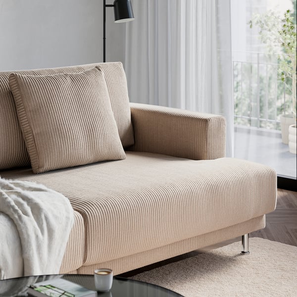 Beige striped sofa with cushions near a large window, offering a comfortable and airy seating area.