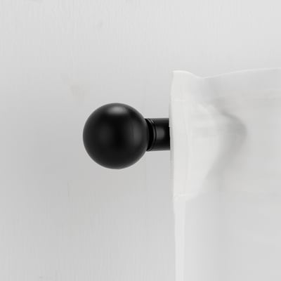 A VÄSENTLIG black finial. It is small, round, and simple, made from recycled plastic. It mounts onto a curtain rod.