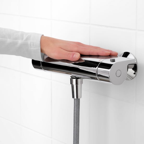 Person adjusting shower mixer with safety stop and temperature control.
