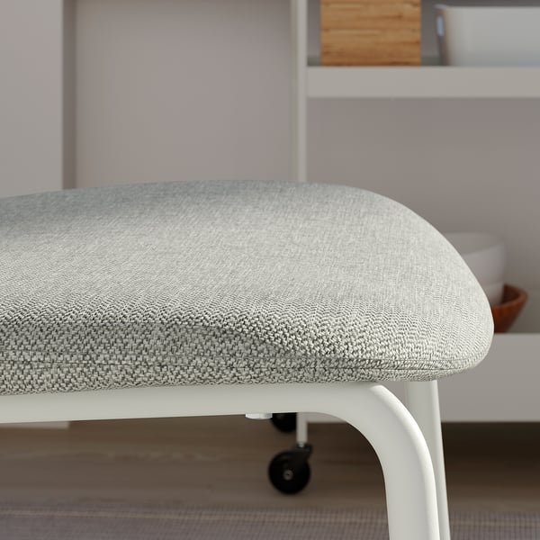 Close-up of a modern cushioned stool with light grey fabric on a sleek white metal frame, positioned under a neatly organised shelf.