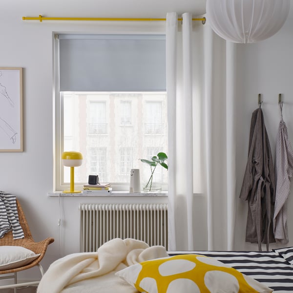 Yellow-curtained bedroom with striped-bed, chair & decor.