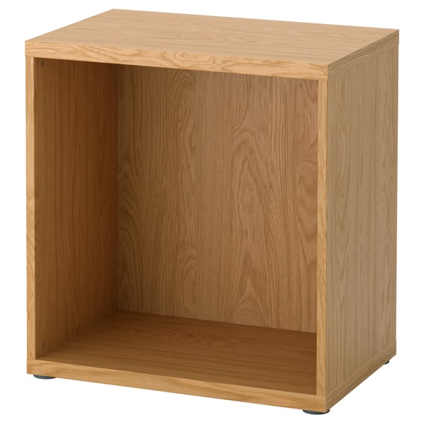 A wooden BESTÅ storage unit in a honey oak colour, rectangular in shape, with an open front and adjustable feet.