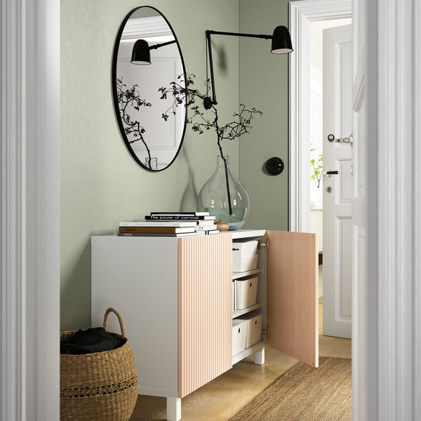 A modern living area a BESTÅ sideboard with adjustable shelves and drawers for storage. An open door reveals organised items inside.