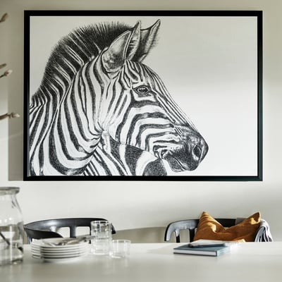 Large zebra portrait framed in black aluminium hangs on a wall over a dining table with chairs.