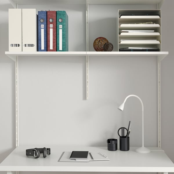 Neat white desk setup with shelves, colourful binders, laptop, and office supplies.