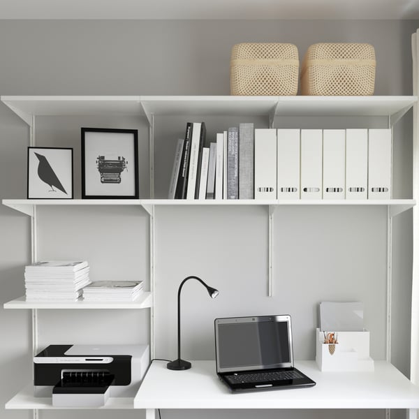Minimalist home office: white shelves store books, printer, laptop, and desk accessories neatly. A stylish and functional workspace.
