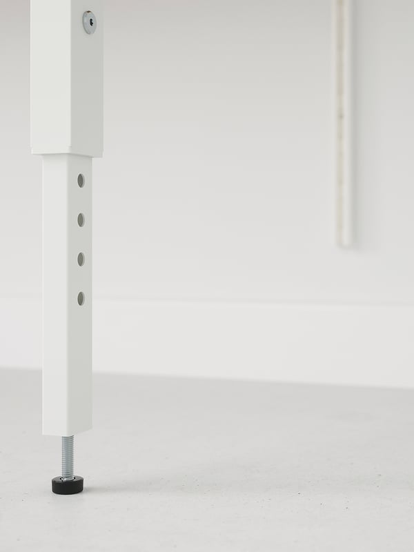 White steel leg with adjustable foot, securely attached to a wall upright using bolts. Part of a sturdy, modern furniture system.