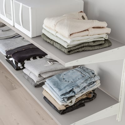 Folded clothes organised on BOAXEL shelves; top shelf holds sweaters, bottom holds jeans and shirts.