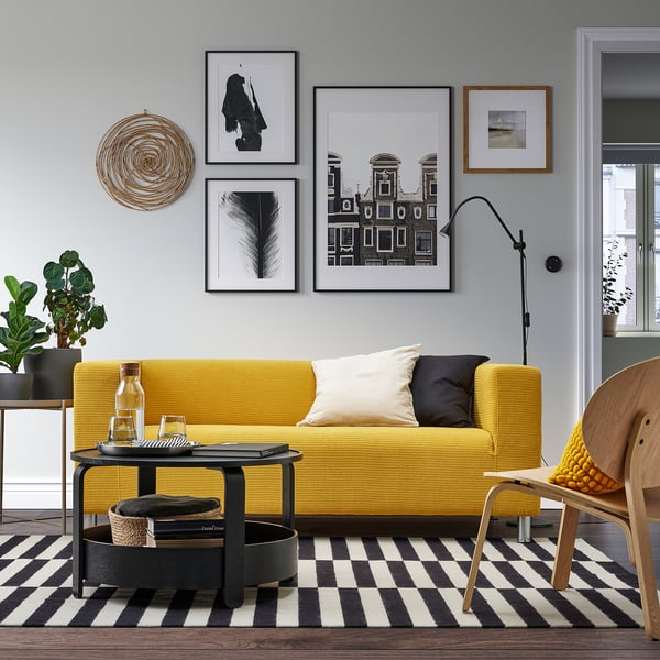 Modern living room with yellow sofa, black & white rug, BORGEBY storage table, and wall art.