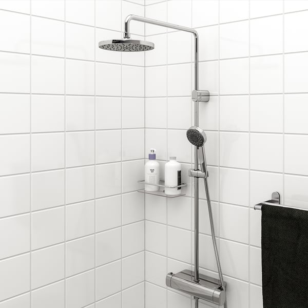 Chrome shower set with handheld & overhead sprays, mounted on white tile with a black towel nearby.