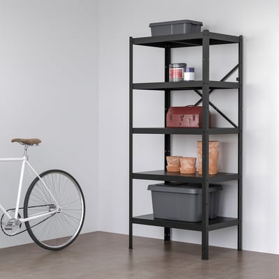BROR: black metal shelf stands tall near white bike; holds grey bins, red box, clay vases. Durable, flexible.