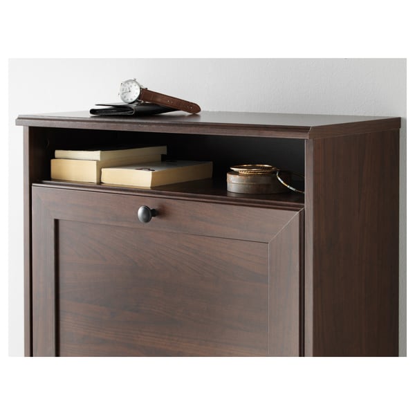Dark wood shoe cabinet with books on top shelf, watch and wallet beside books. Has knobs for drawers.