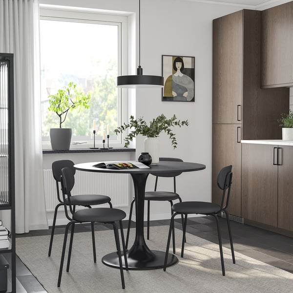 Modern dining setup with DOCKSTA black round table and chairs. Sleek design, matching dark wooden cabinets and minimalistic hanging light.