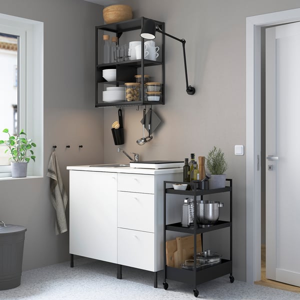 ENHET kitchen: white cabinet with black accents, stainless steel sink, and a small cart next to it.