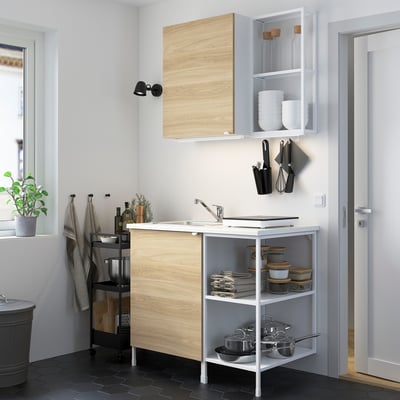 Modern compact kitchen: light wood cabinet, white sink, black accessories, stainless steel sink, compact design.
