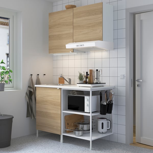 Minimalist kitchen: wood front, white, stainless steel sink, microwave, & electric kettle. Compact size.