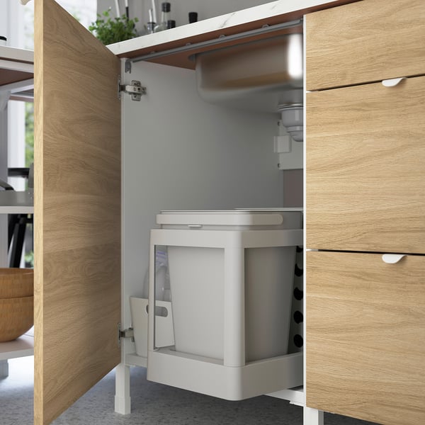 Kitchen cabinet with integrated waste sorting system under countertop.