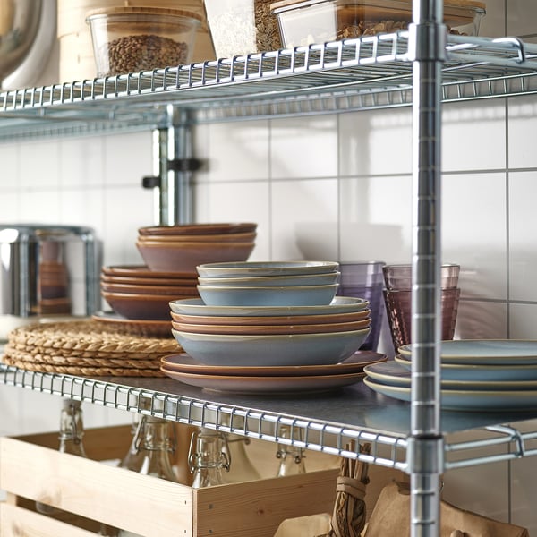 Metal kitchen shelf holding plates, bowls, and cups.