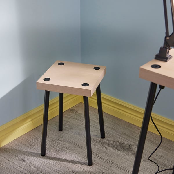 Two FRIDNÄS nesting tables with black legs and wooden tops in a corner.