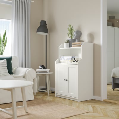White HAUGA cabinet with decor, plant, lamp, and armchair.