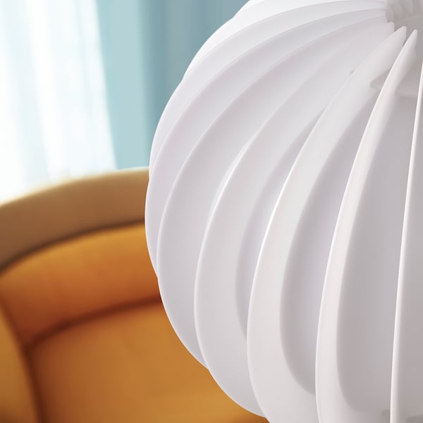 White spiral lampshade next to yellow couch.