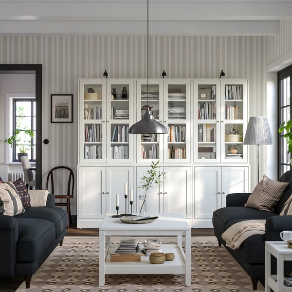 New living room: HAVSTA white pine bookshelves, grey couches, black pendant light, patterned rug, coffee table with decor and pillows.
