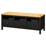 A black and light wood HEMNES tv bench. It three drawers, open storage, and solid pine construction.