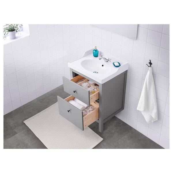 Bathroom vanity with open drawers, sink, towel hook, and toiletries.