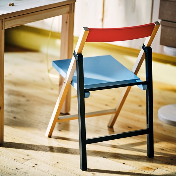 IKEA PS 2026: red-blue foldable chair, metal & wood mix, sleek, modern design. Compact size fits near table, easy to store.
