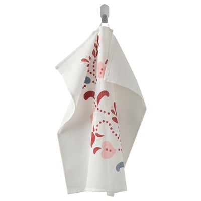 The INAMARIA towel, white with red and pink floral prints, hangs on a hook. Made of 100% cotton, its loop allows easy hanging.