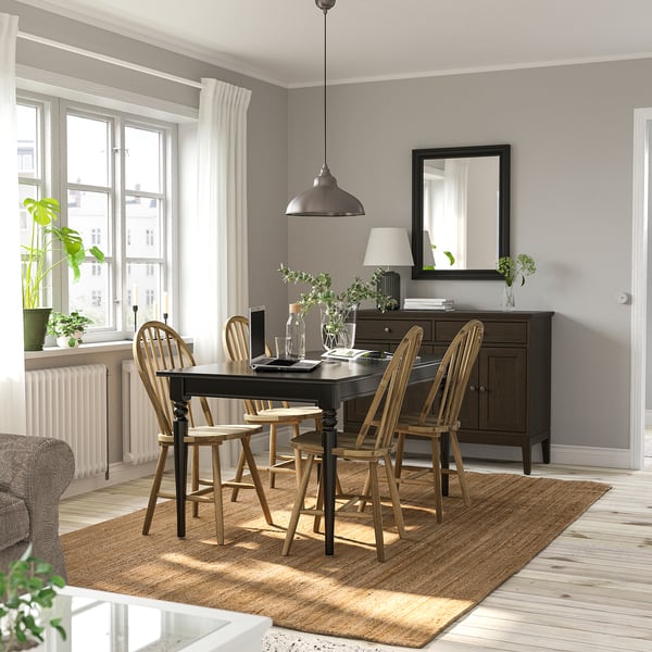 Cosy dining room with black extendable INGATORP table, wooden chairs, and a rug. Near window with curtains, dark cabinet with mirror.