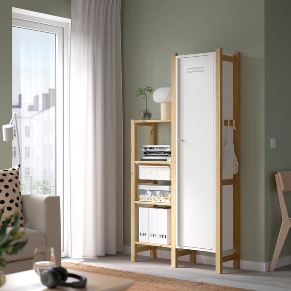 White IVAR cabinet by window, with books & lamp. Steel & pine, modern minimalist decor.